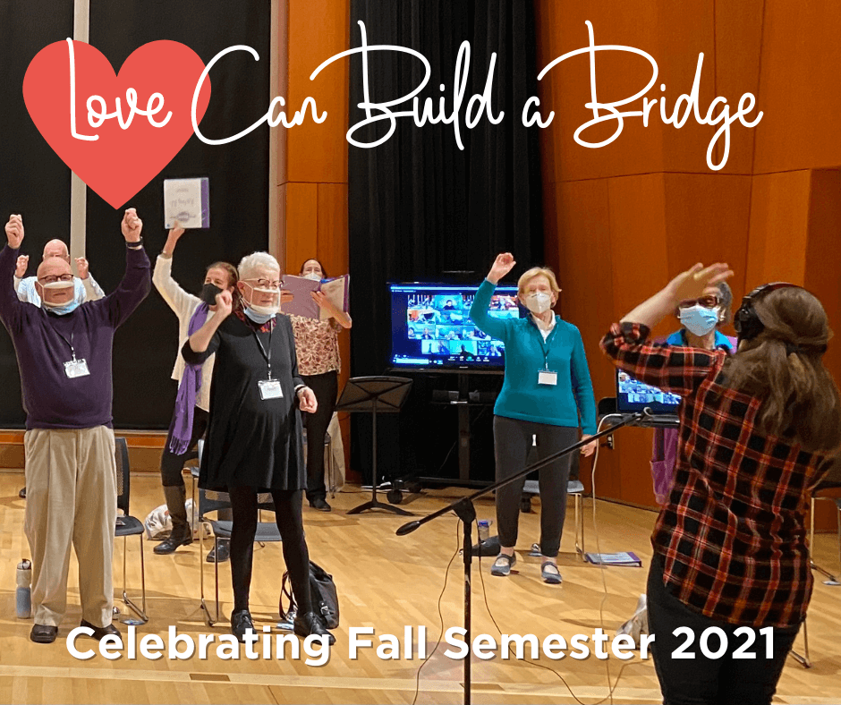 Photo from our Fall Semester Celebration, People standing to sing with their arms raised to say hooray